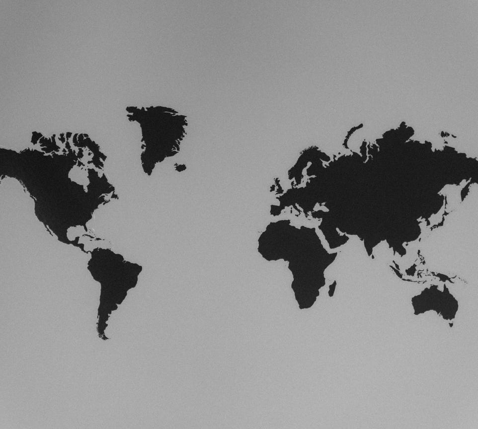 A simple black and white silhouette of a world map emphasizing continents against a stark background.
